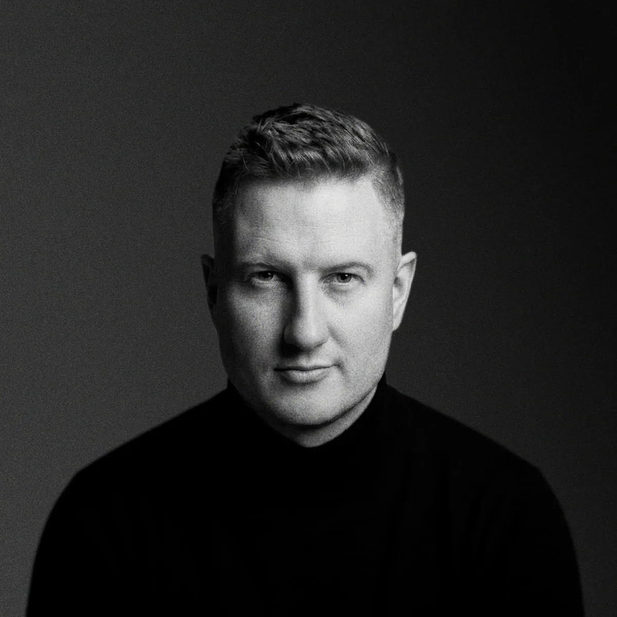 Grigory Vyatkin, černobílý portrét v tmavém roláku na tmavém pozadí